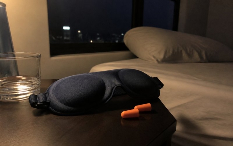 Schlafmaske und Ohrstöpsel auf dem Nachttisch